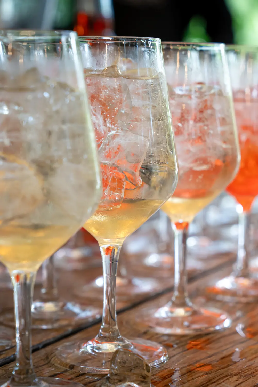 Fila di calici di spritz allineati sul banco dell'aperitivo