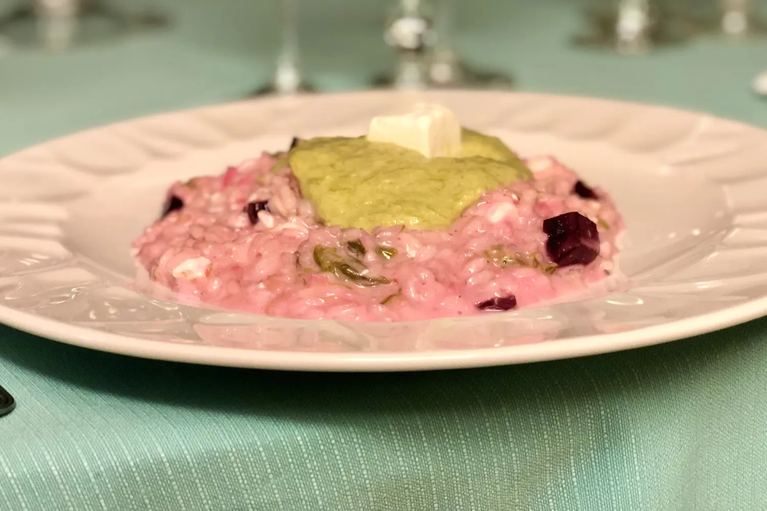 Risotto rosa con crema verde e cubetto di formaggio, tavola verde acqua e calici